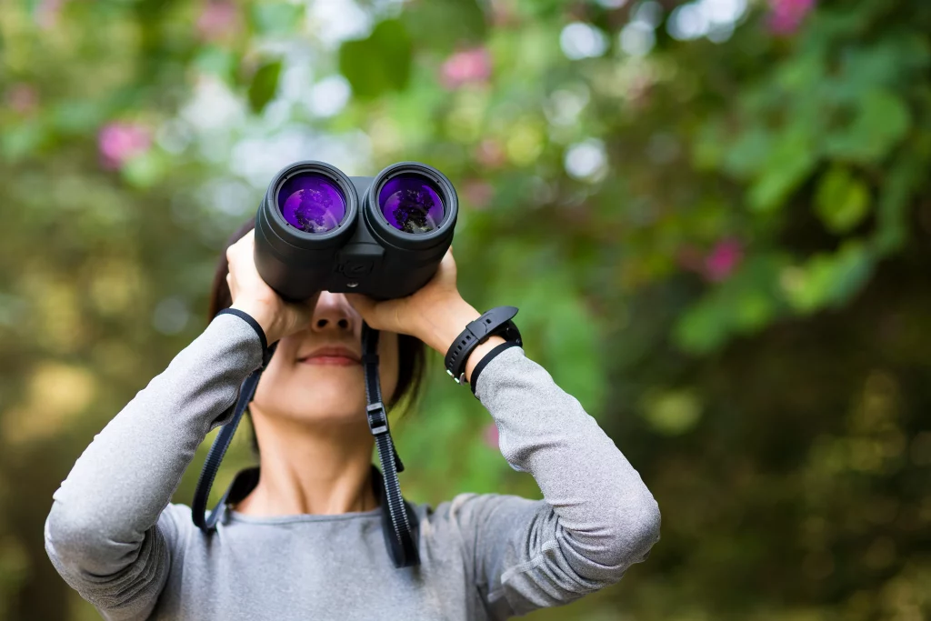 Personne observant aux jumelles, symbole de la veille active plutôt que de l'attentisme